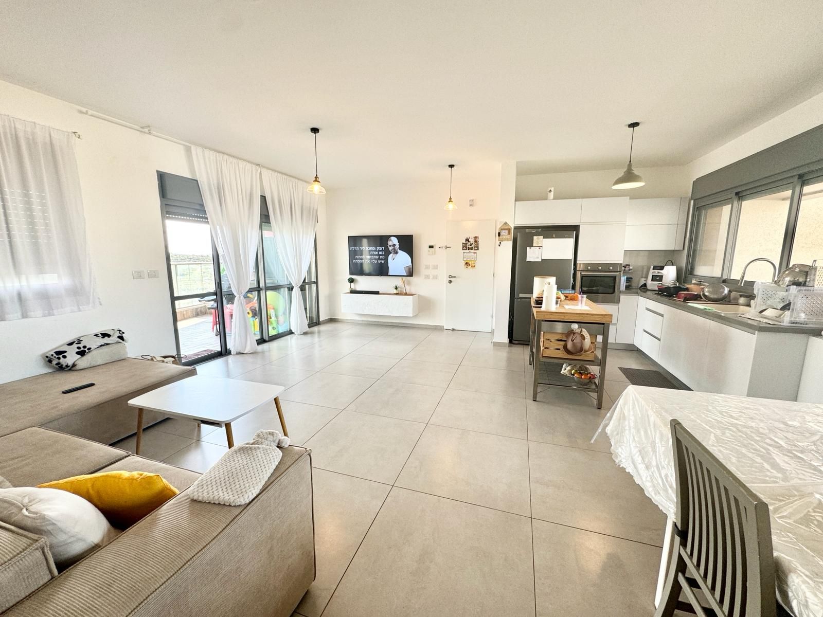 סלון עם ספה, שולחן, כיסאות וטלוויזיה.