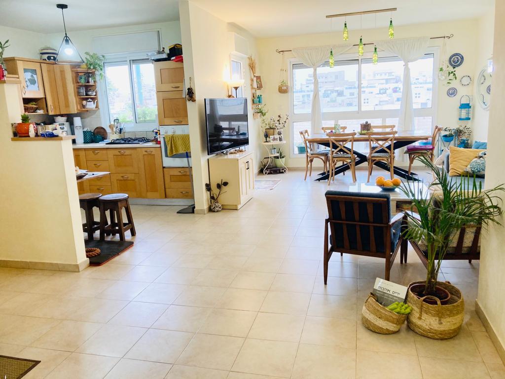 סלון עם שולחן אוכל וכיסאות ומטבח.