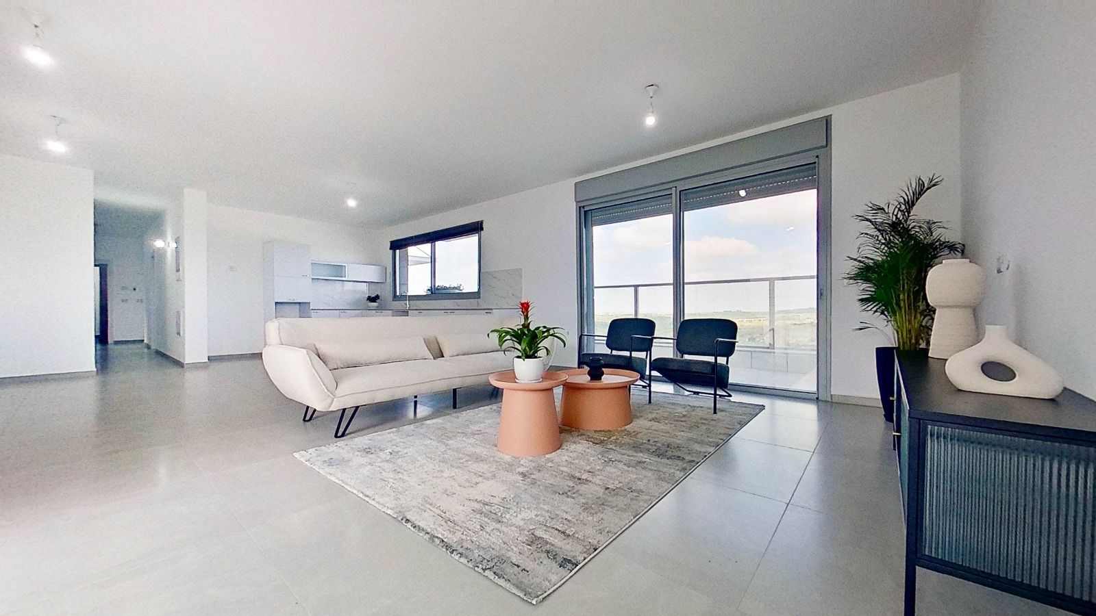 סלון עם ספה, כיסאות, שולחנות ומרפסת.