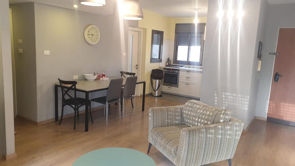 סלון עם שולחן וכיסאות ושעון על הקיר.