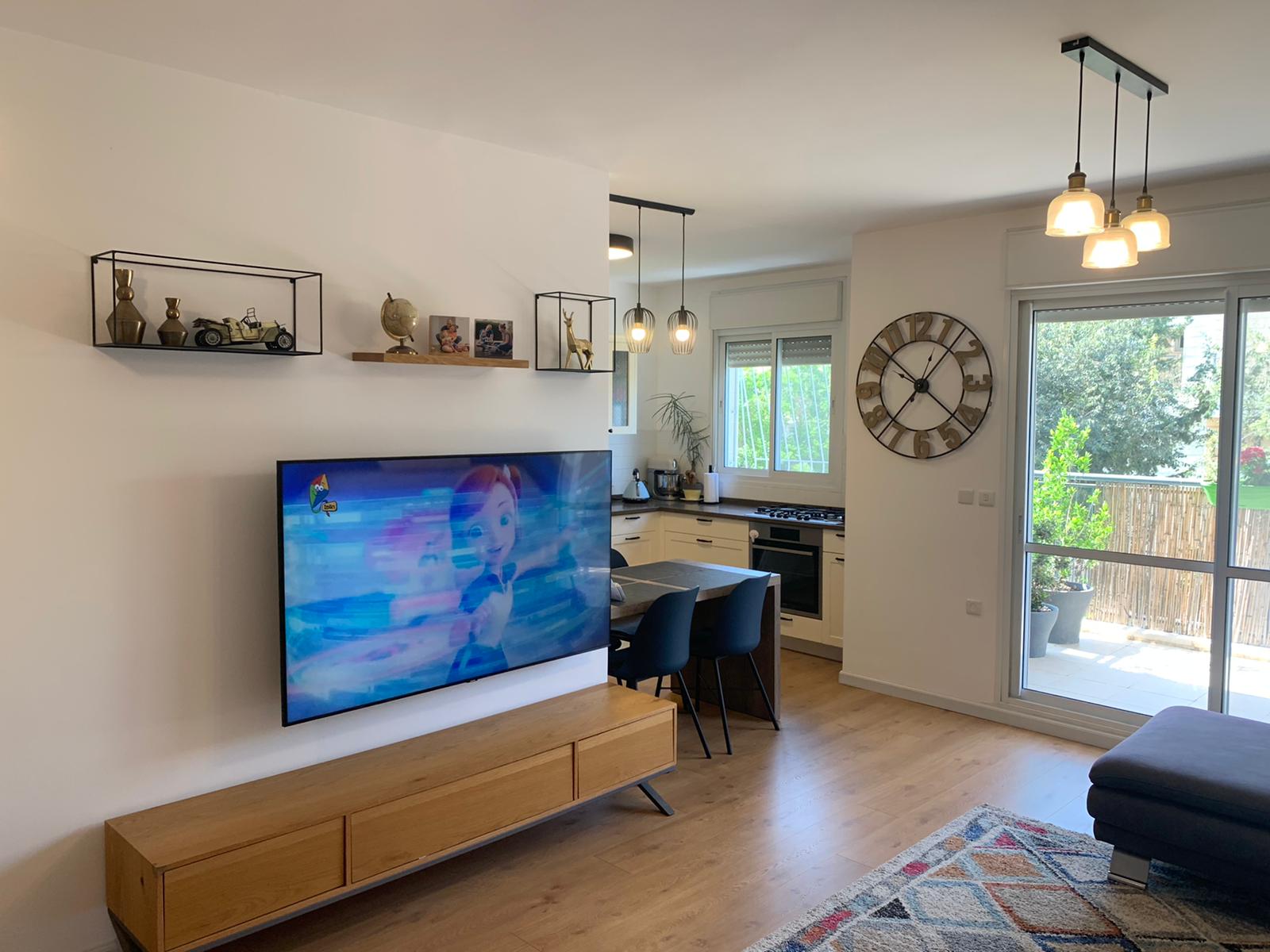 סלון עם טלוויזיה בעלת מסך שטוח ושעון על הקיר.