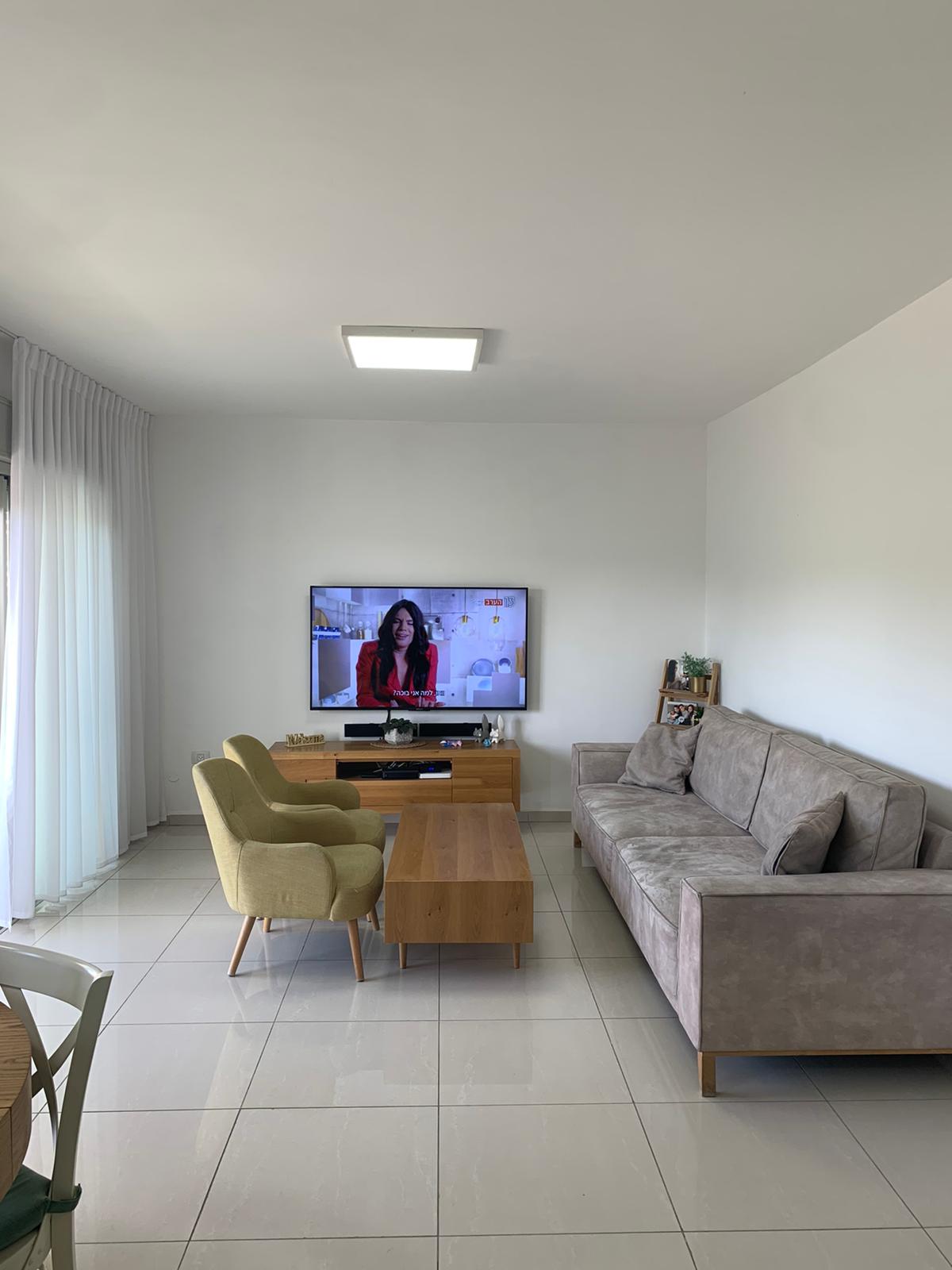 סלון עם ספה, כיסאות, שולחן קפה וטלוויזיה.