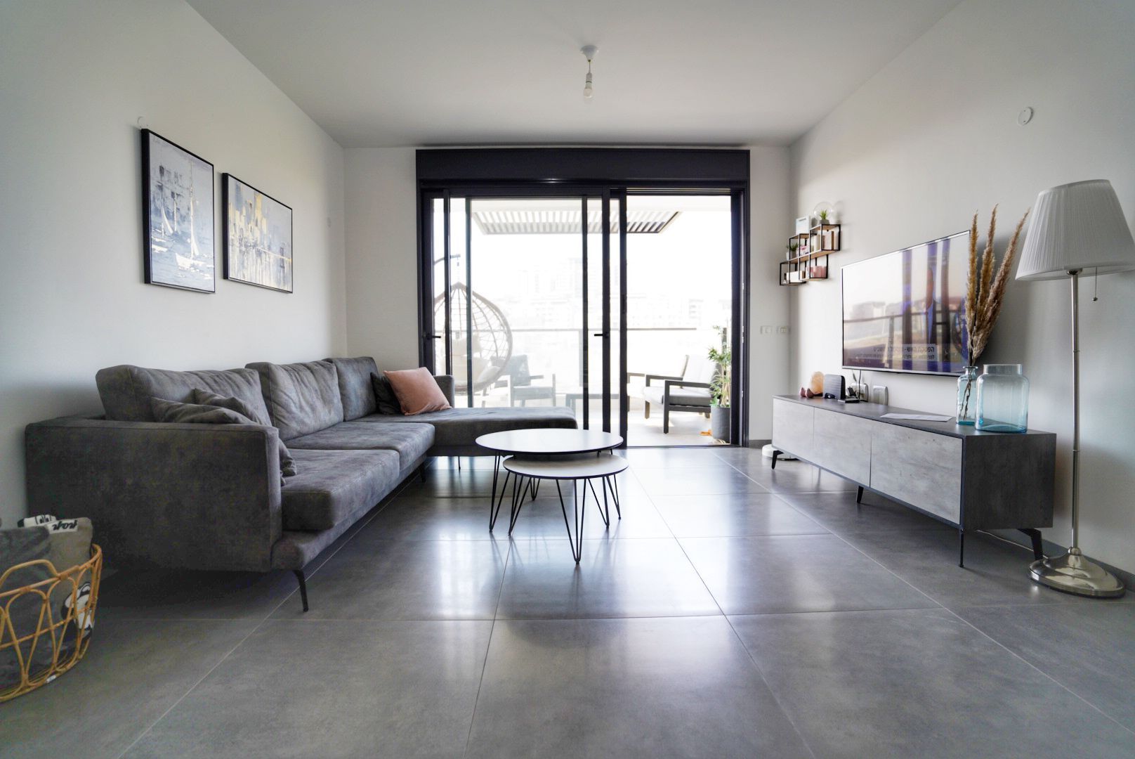 סלון עם ספה, שולחן, טלוויזיה ודלתות הזזה מזכוכית.