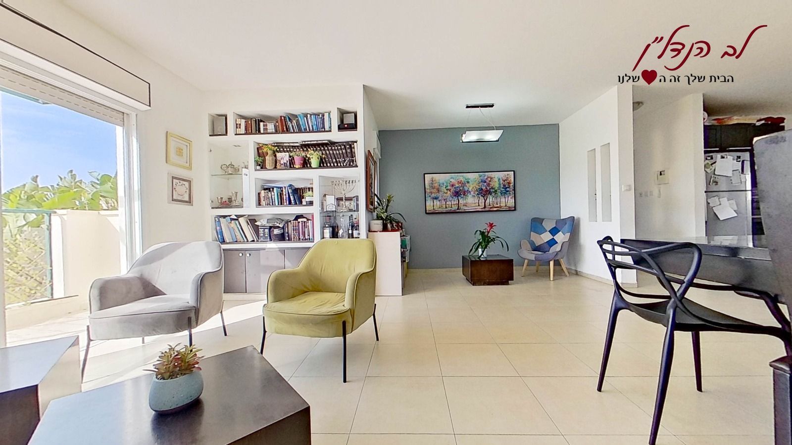 סלון עם שולחן וכיסאות ומדף ספרים.