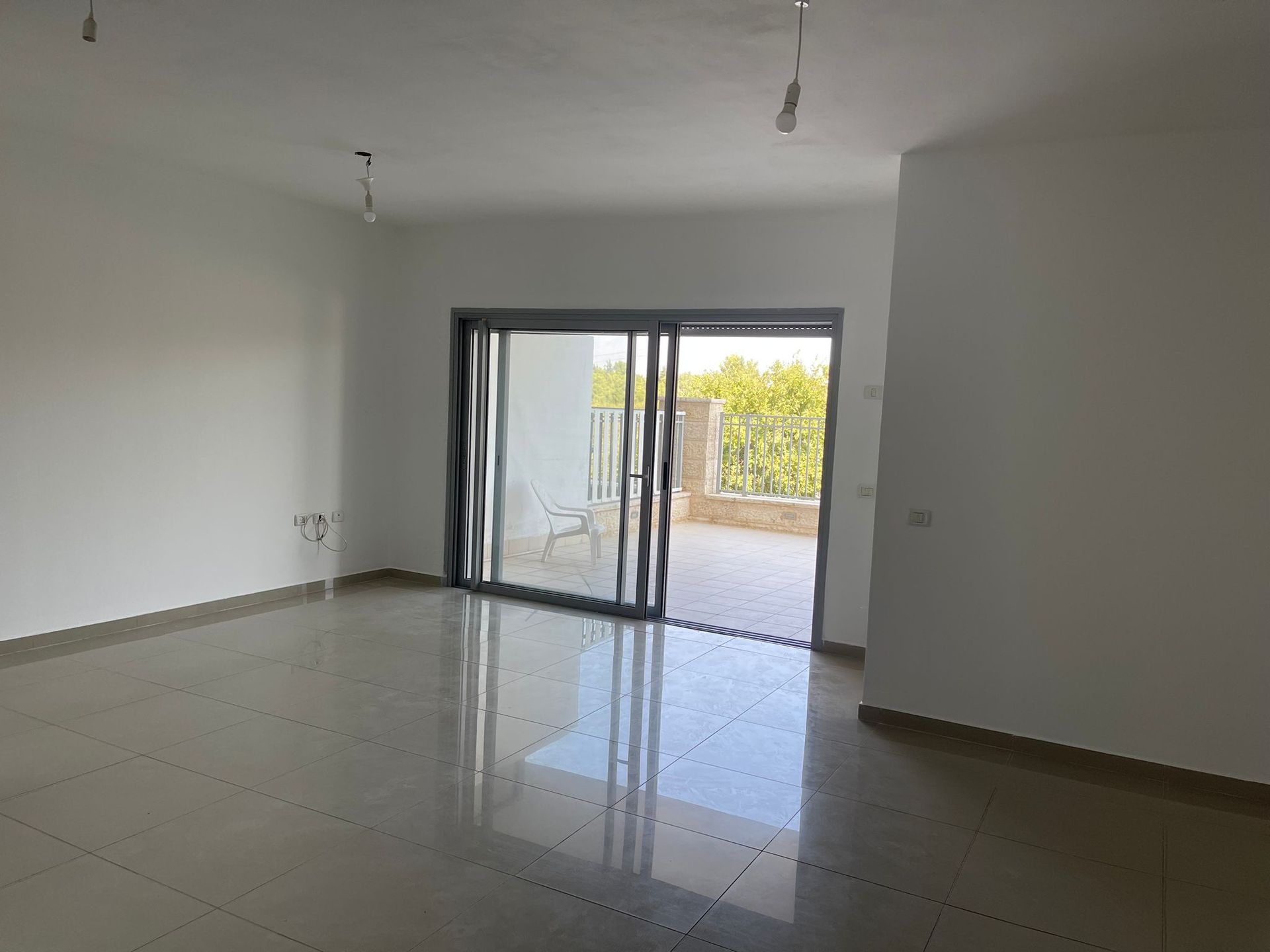 סלון ריק עם דלת הזזה מזכוכית המובילה למרפסת.