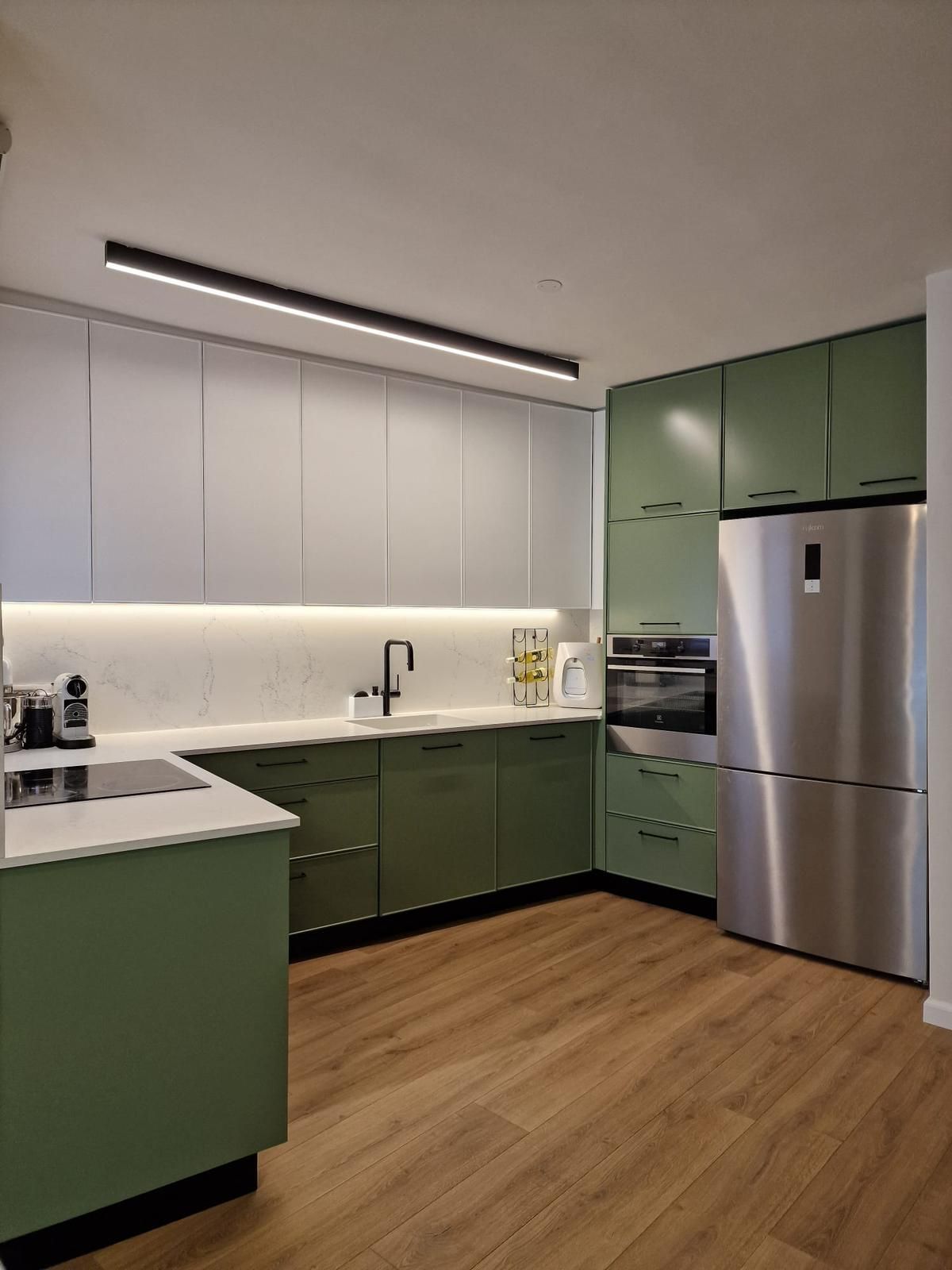 מטבח עם ארונות ירוקים ומוצרי נירוסטה