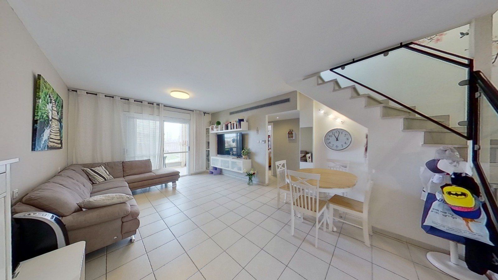 סלון עם ספה, שולחן, כיסאות ומדרגות.