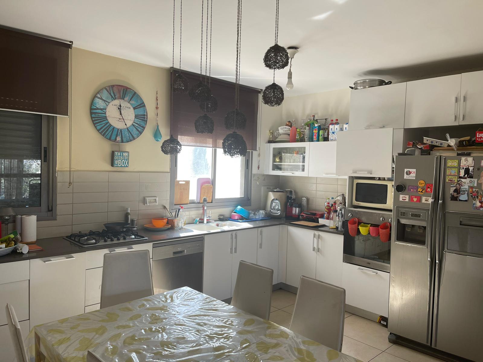 מטבח עם שולחן וכיסאות ושעון על הקיר