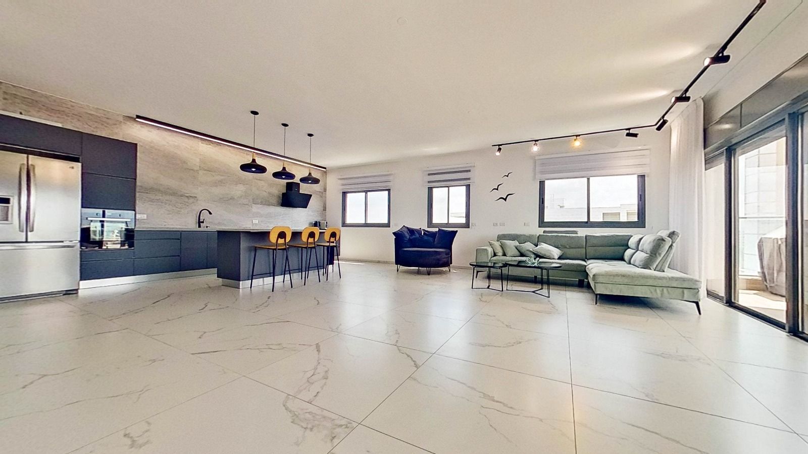 סלון עם ספה, כיסאות ומטבח.