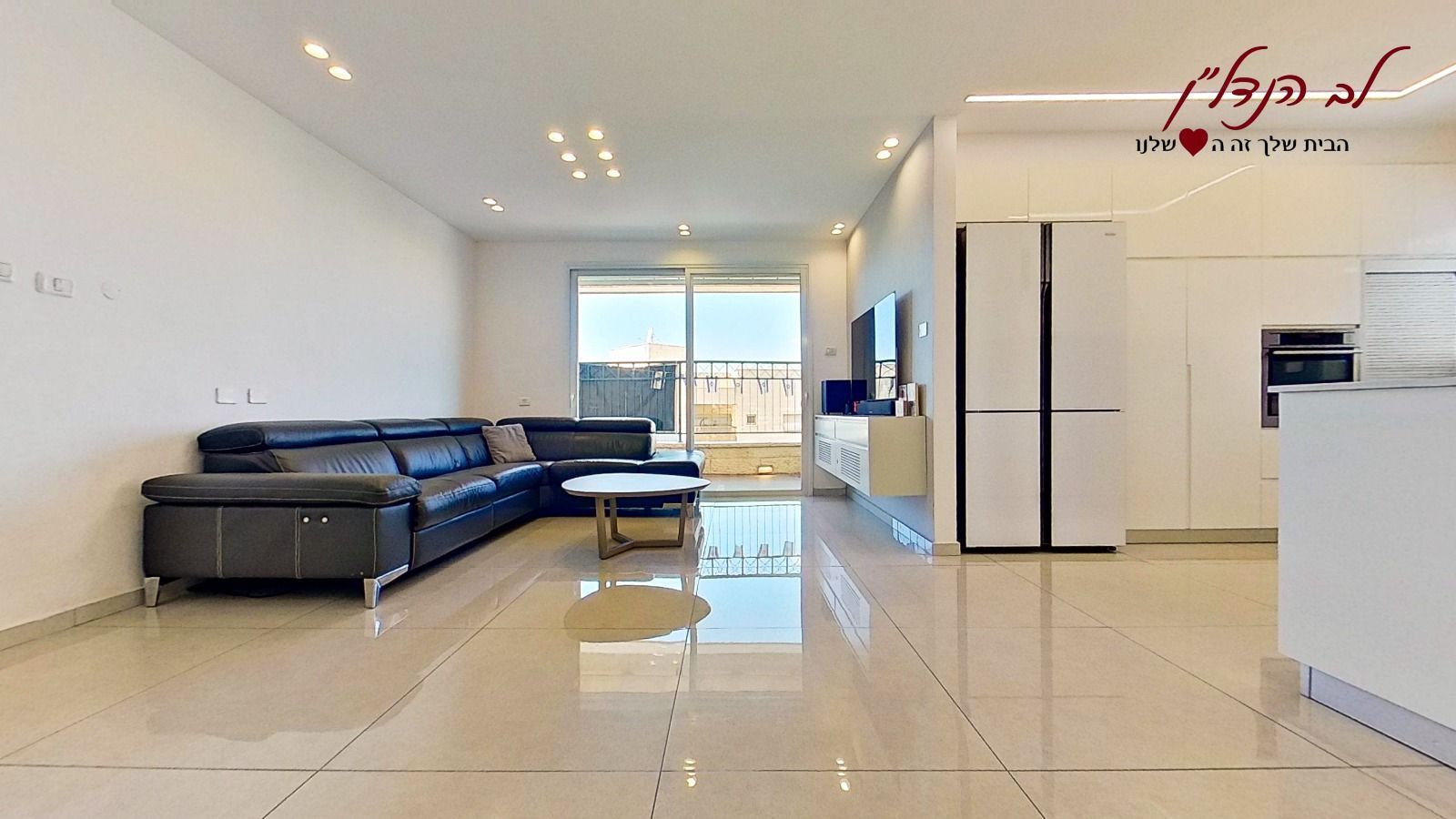 סלון עם ספת חתך שחורה, שולחן קפה ומקרר.