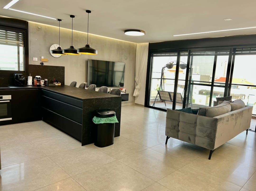 סלון עם ספה, כיסאות ומטבח.