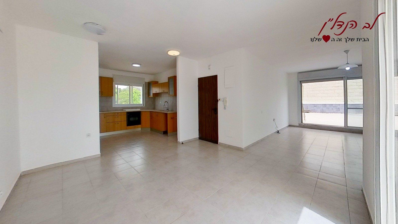 סלון ריק עם מטבח ברקע