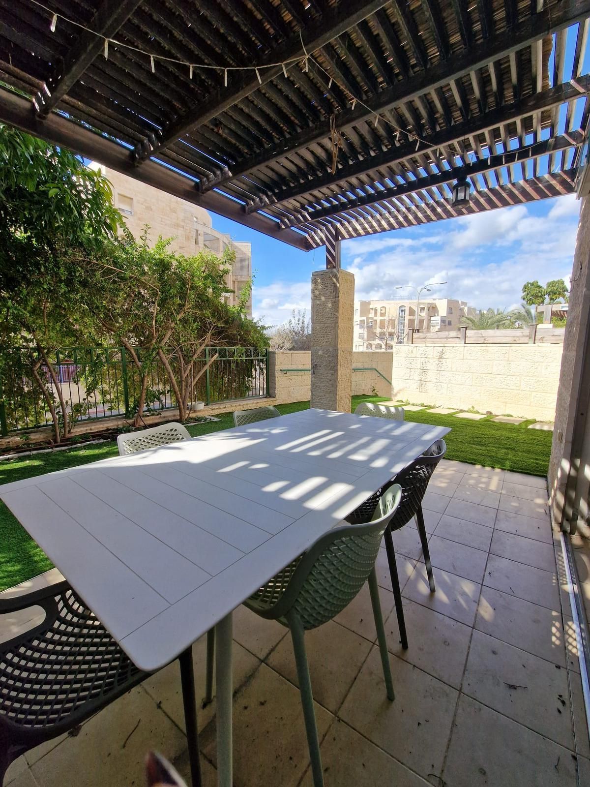 פטיו עם שולחן וכיסאות מתחת לפרגולה