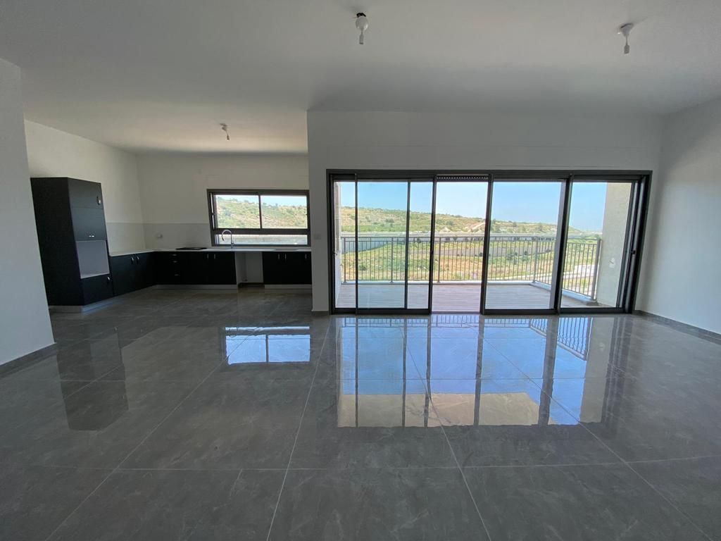 חדר ריק גדול עם דלתות הזזה מזכוכית ומרפסת.