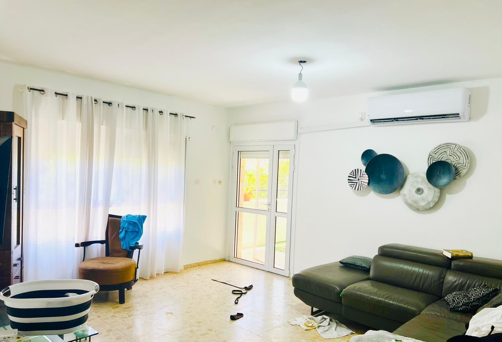 סלון עם ספה, כיסא, אגרטל ומזגן.