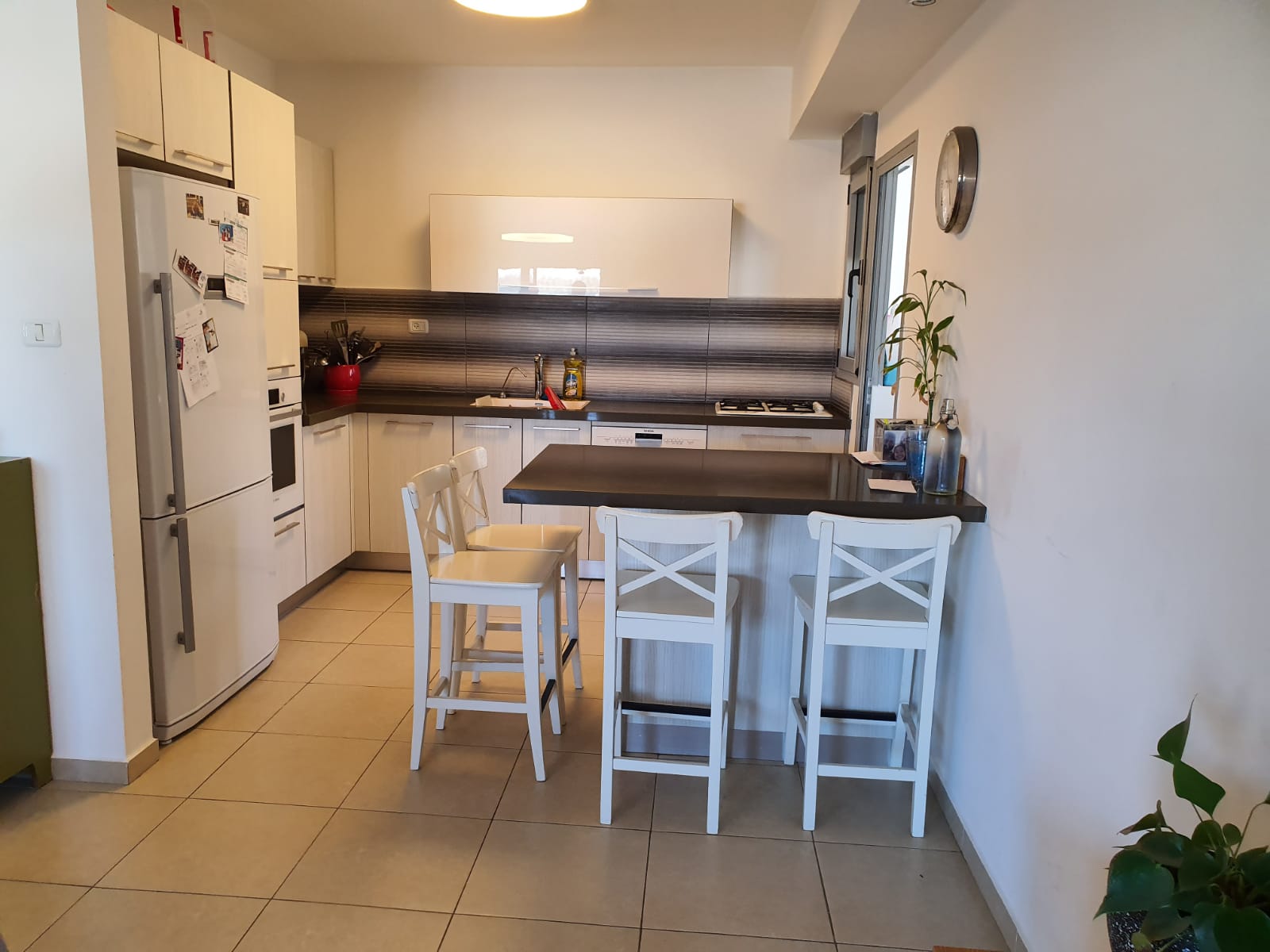 מטבח עם שולחן וכיסאות ומקרר.