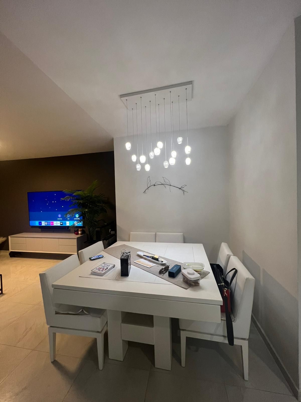 חדר אוכל עם שולחן וכיסאות וטלוויזיה על הקיר.