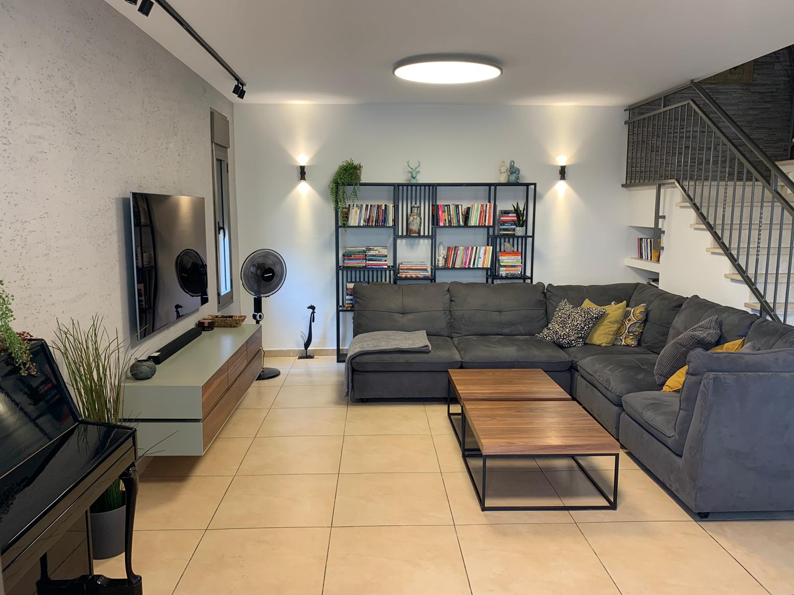 סלון עם ספה חלקית גדולה, שולחן קפה וטלוויזיה.