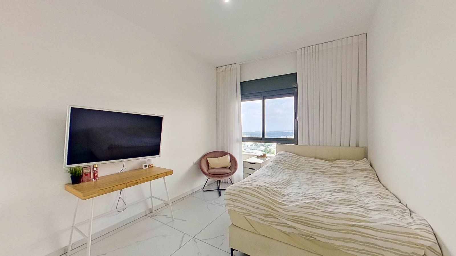 חדר שינה עם מיטה, טלוויזיה, שולחן עבודה וכיסא.