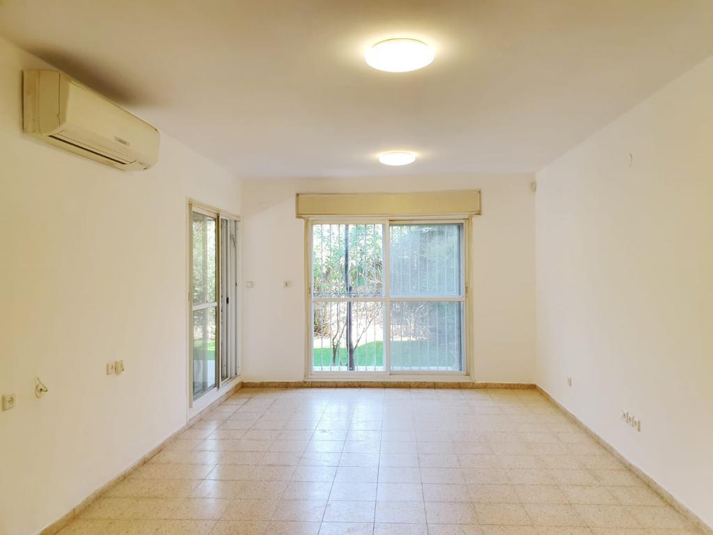 סלון ריק עם דלתות הזזה מזכוכית ומאוורר תקרה.