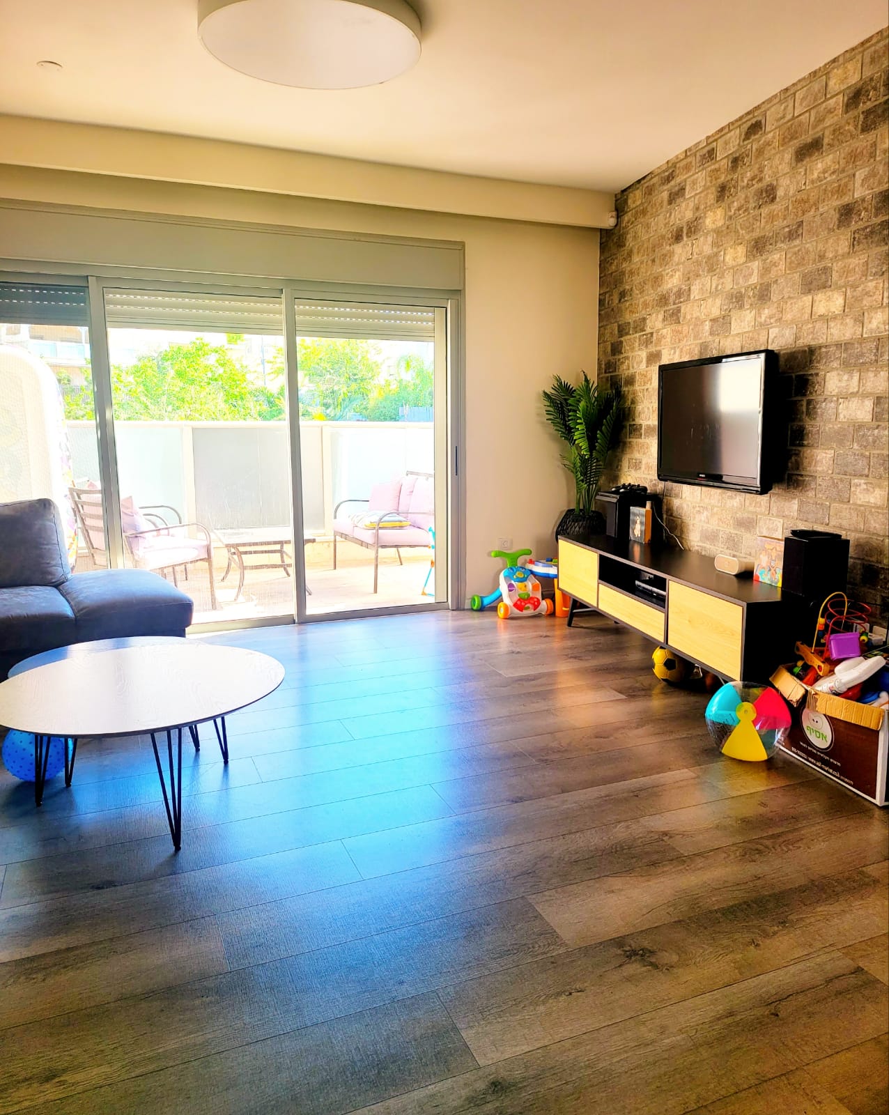 סלון עם ספה, שולחן, טלוויזיה וצעצועים.