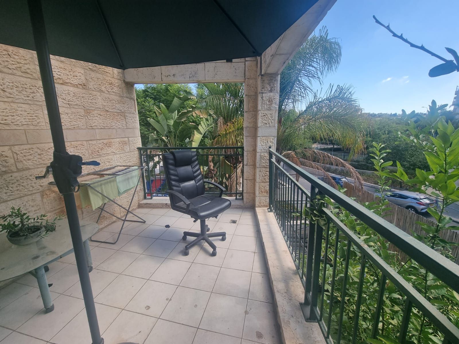 כיסא יושב על מרפסת מתחת למטריה.