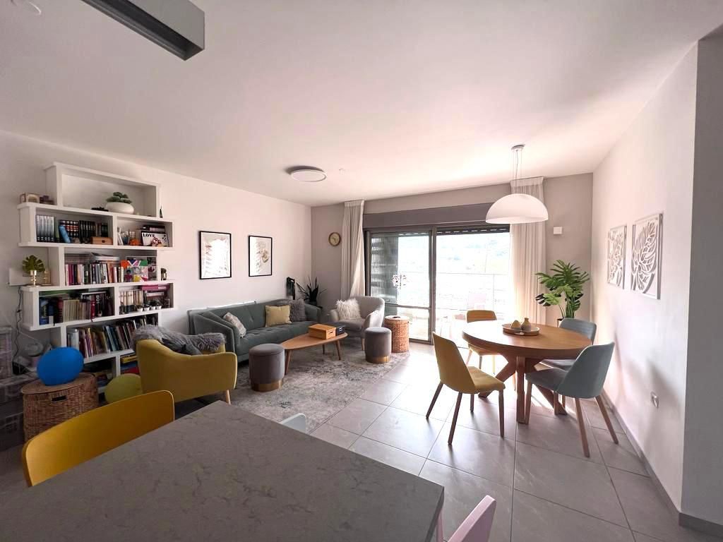 סלון עם ספה, כיסאות, שולחן ומדף ספרים.