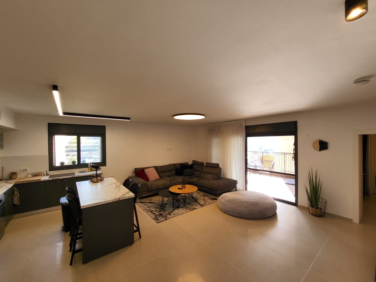 סלון עם ספה, שולחן, כיסאות ומרפסת.