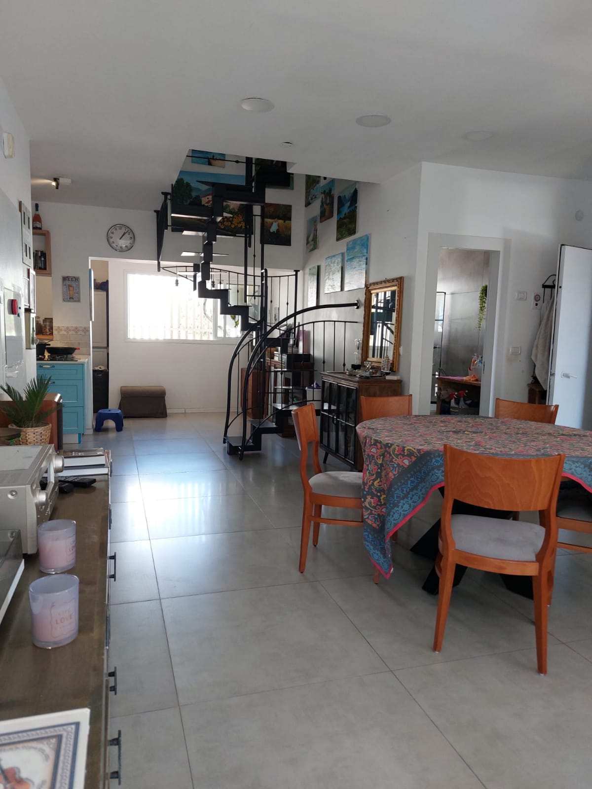 סלון עם שולחן וכיסאות וגרם מדרגות לולייניות.