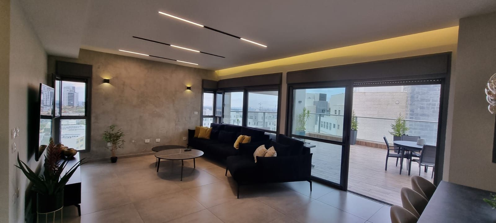 סלון עם ספה, שולחן, כיסאות ודלתות הזזה מזכוכית.