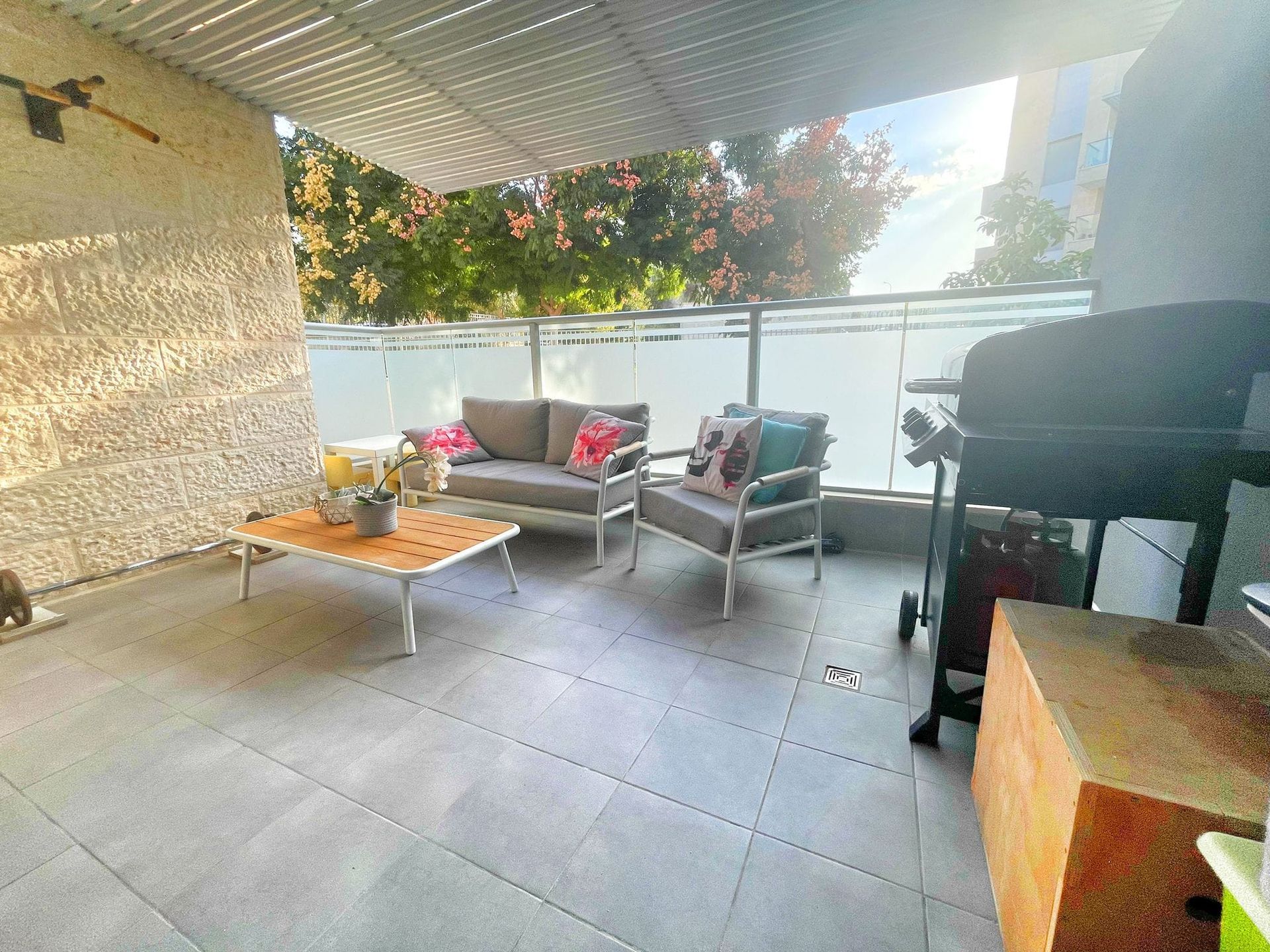 פטיו עם ספה, כיסאות, שולחן וגריל.