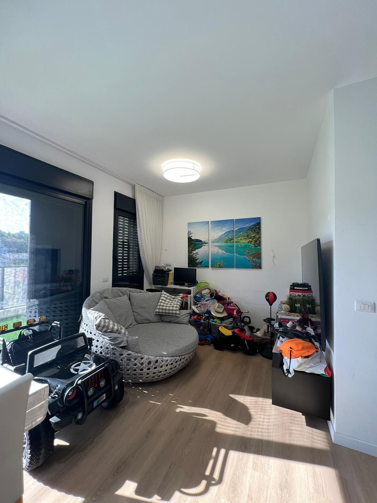 סלון עם כיסא עגול גדול והרבה צעצועים על הרצפה.