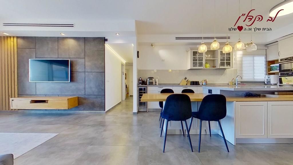 מטבח עם שולחן וכיסאות וטלוויזיה בעלת מסך שטוח על הקיר.