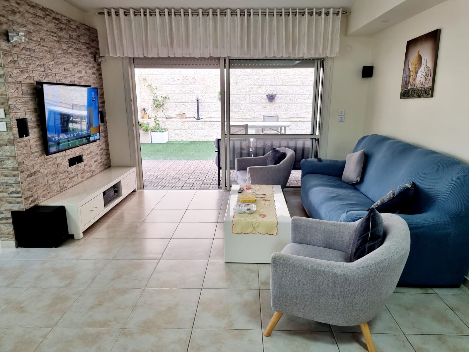 סלון עם ספה, כיסאות וטלוויזיה בעלת מסך שטוח.