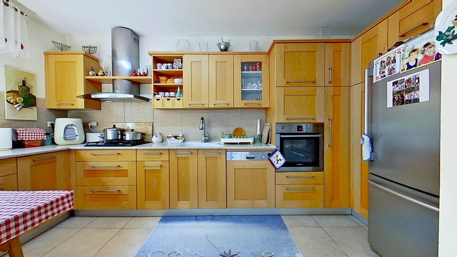 מטבח עם ארונות עץ ומקרר נירוסטה.