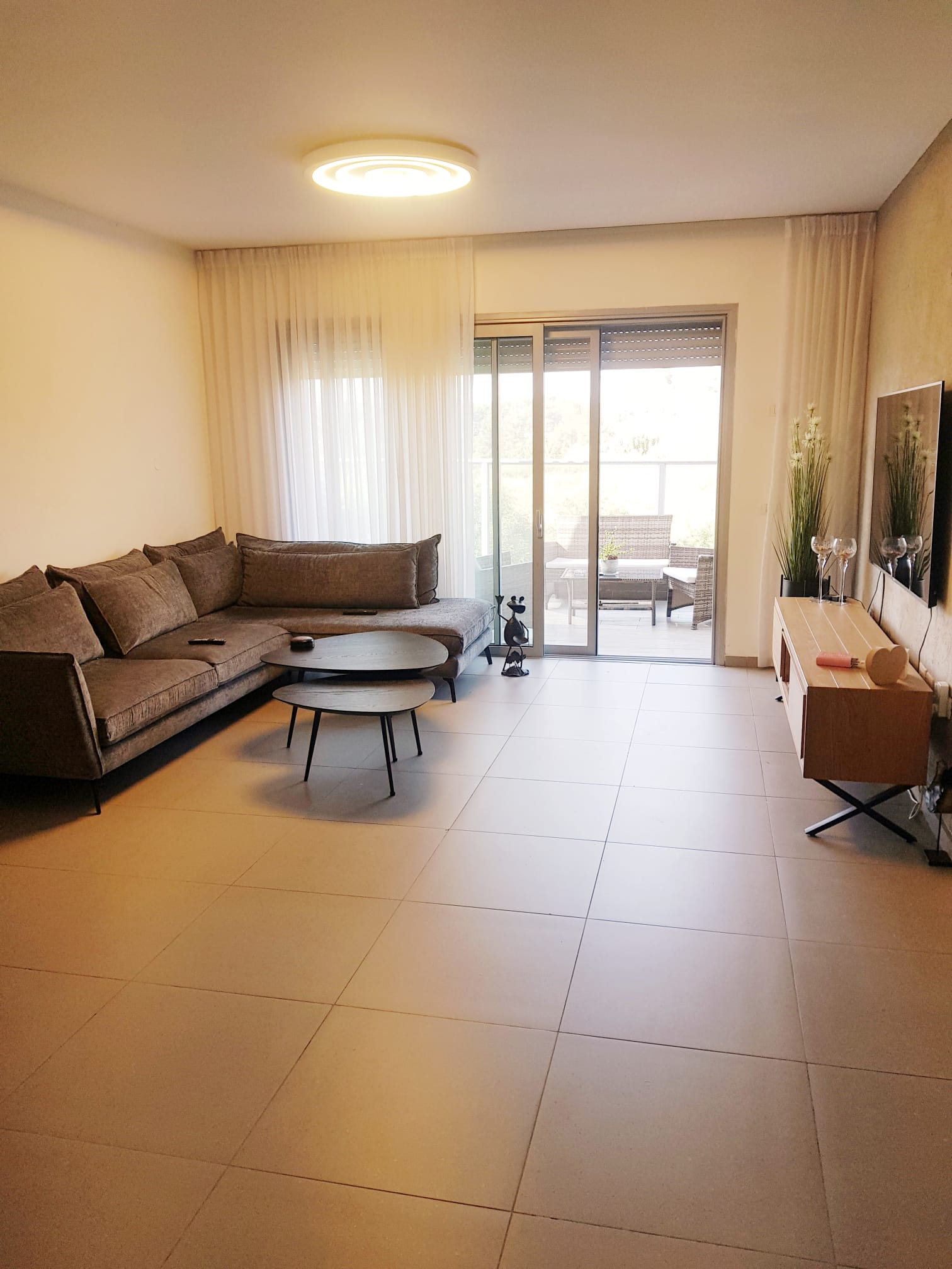 סלון עם ספה, שולחן, טלוויזיה ודלתות הזזה מזכוכית.