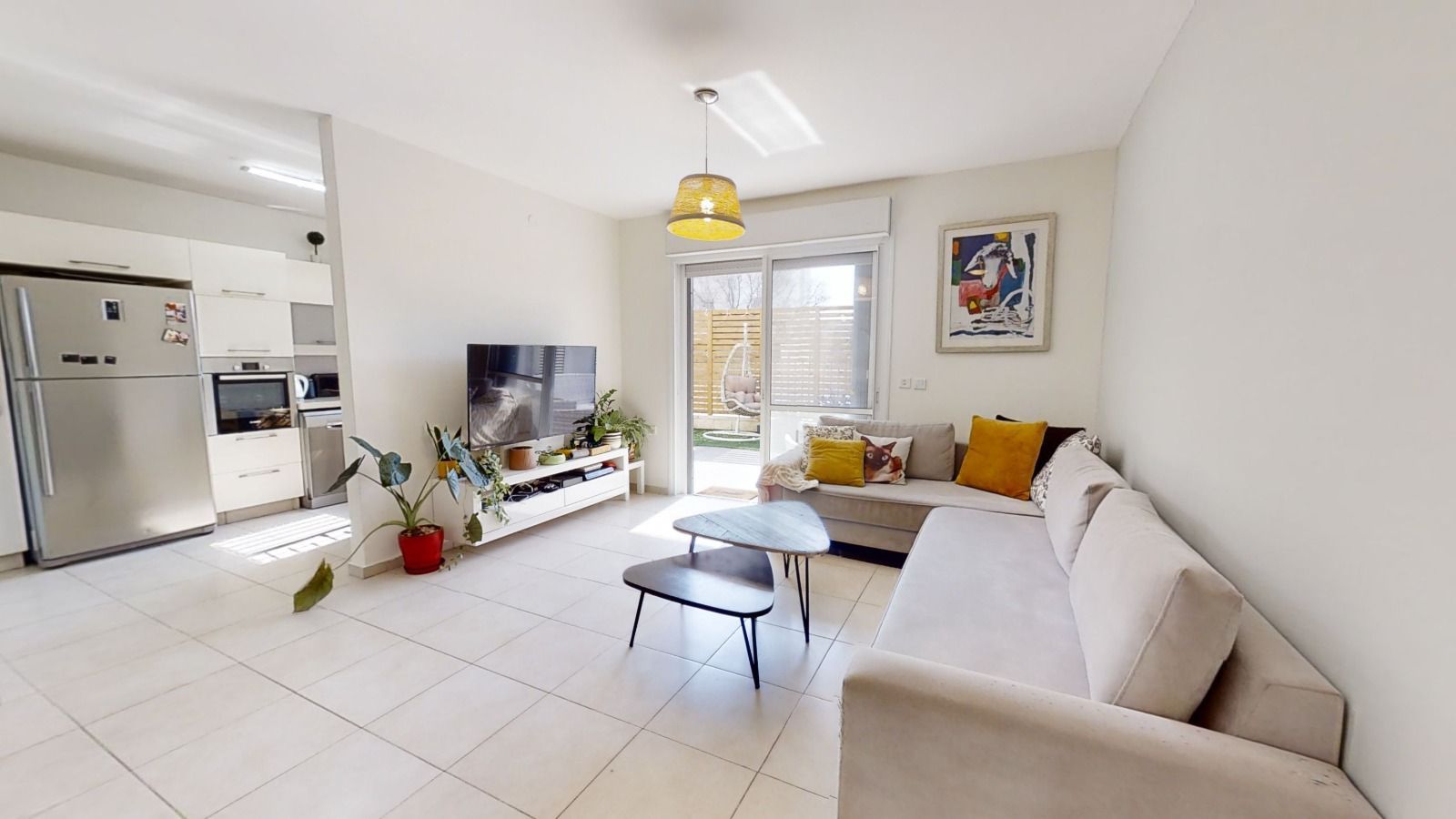 סלון עם ספה, שולחן, טלוויזיה ומקרר.