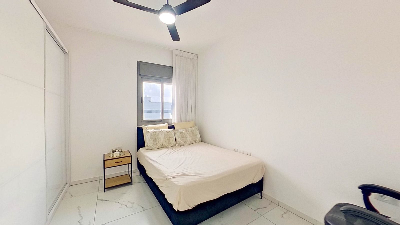 חדר שינה עם מיטה, שידת לילה ומאוורר תקרה.