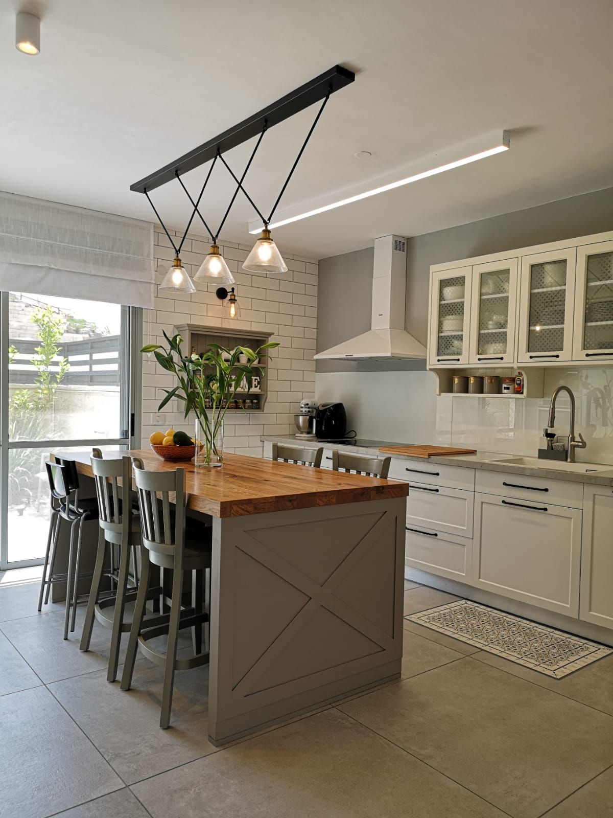 מטבח עם ארונות לבנים , אי עץ , שרפרפים וכיור.