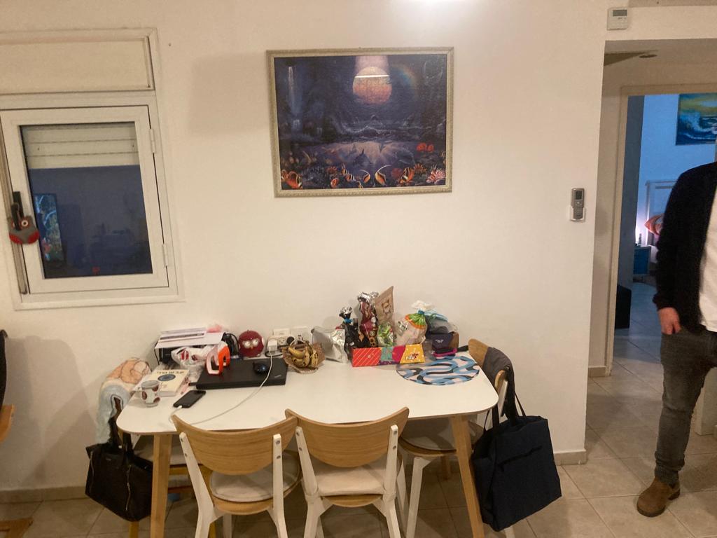 גבר עומד בחדר עם שולחן וכיסאות ותמונה על הקיר.