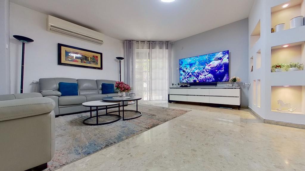 סלון עם ספה, שני שולחנות קפה וטלוויזיה בעלת מסך שטוח.