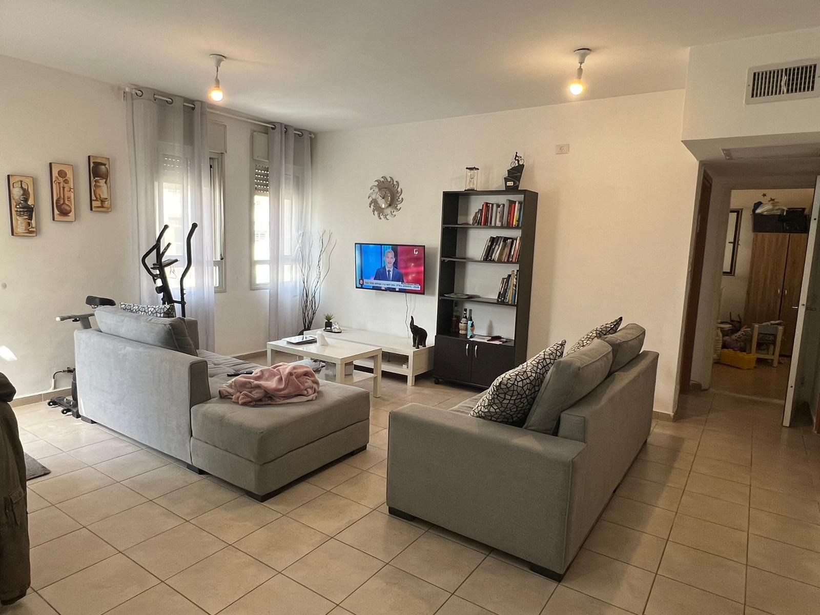 סלון עם שתי ספות וטלוויזיה על הקיר.