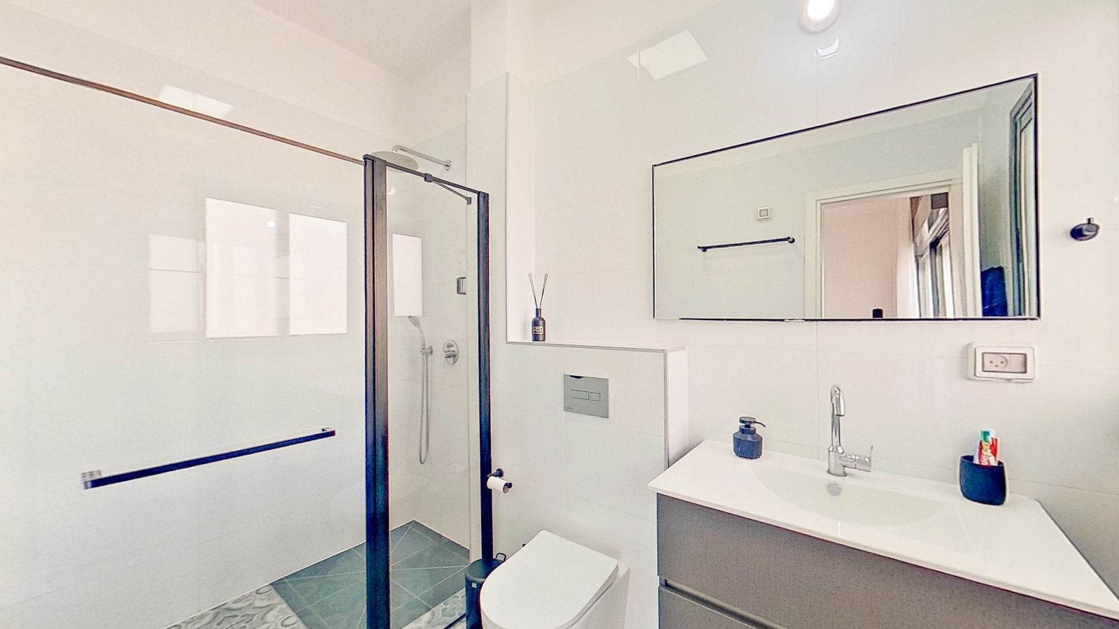 חדר רחצה עם שירותים, כיור, מקלחת ומראה.