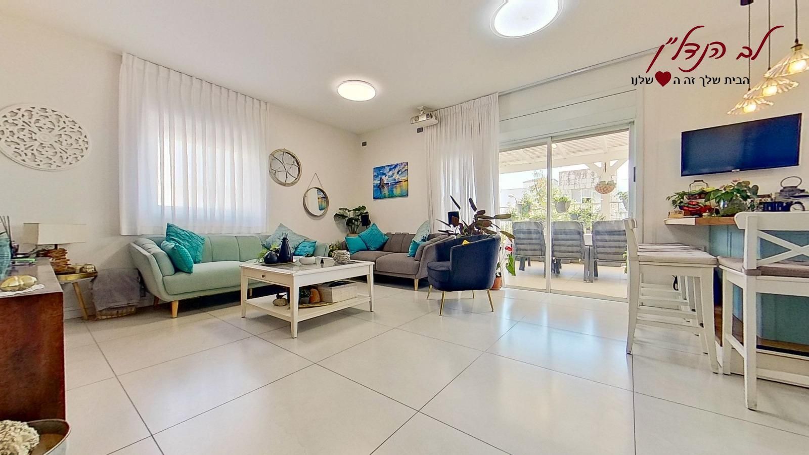 סלון עם ספה, שולחן, כיסאות וטלוויזיה.