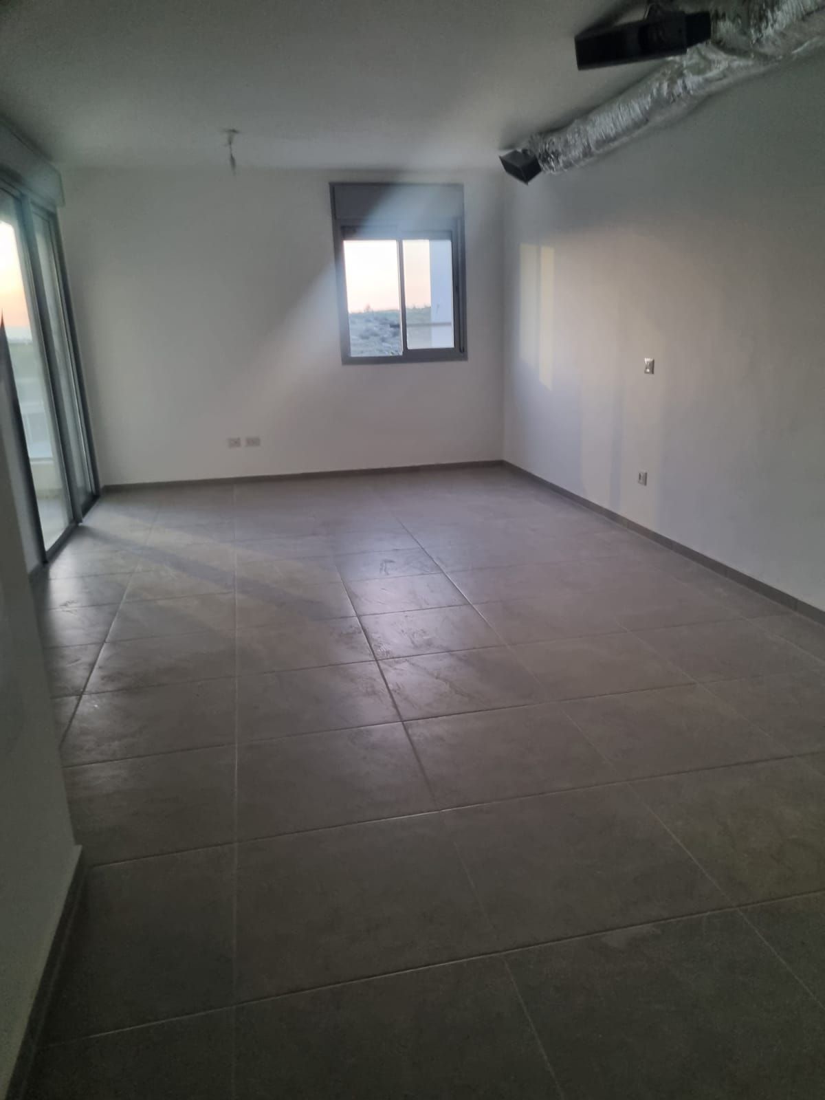 חדר ריק גדול עם רצפת אריחים וחלון.
