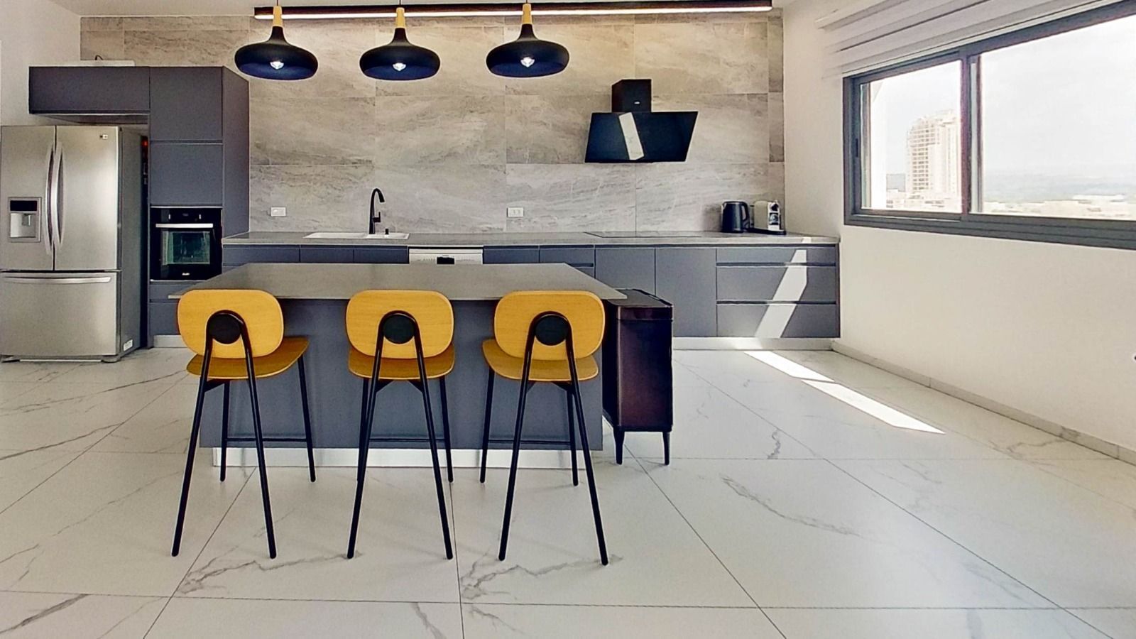 מטבח עם אי גדול, שרפרפים ומקרר.