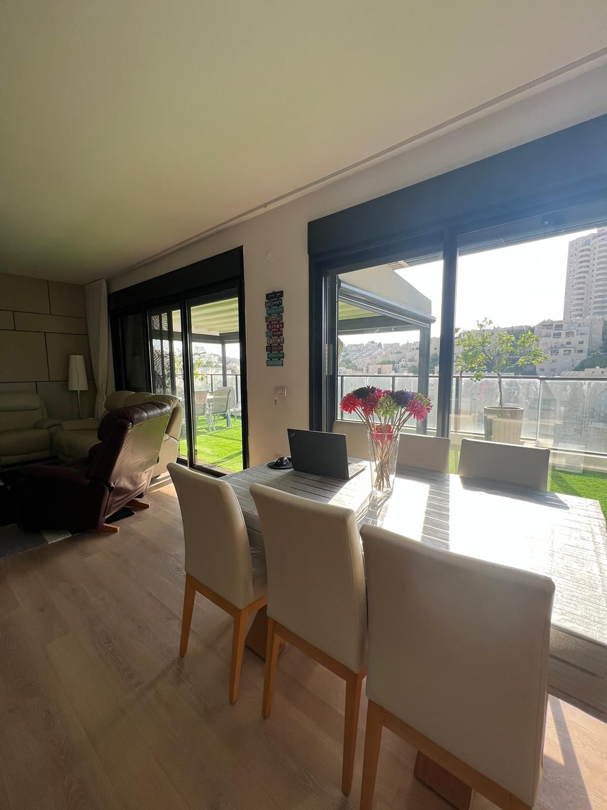 סלון עם שולחן אוכל וכיסאות ומחשב נייד עליו.