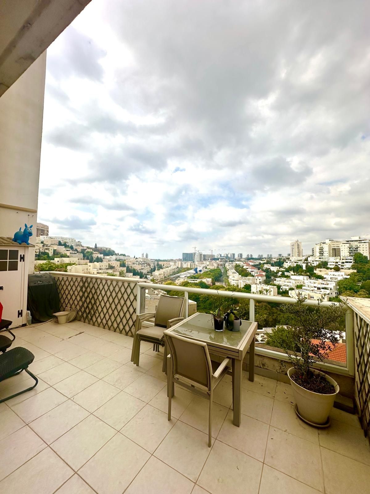 מרפסת עם שולחן וכיסאות ונוף לעיר.