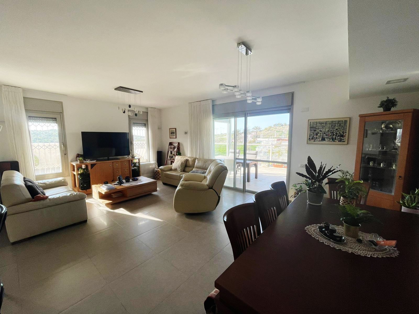 סלון עם שולחן אוכל וכיסאות וטלוויזיה בעלת מסך שטוח.