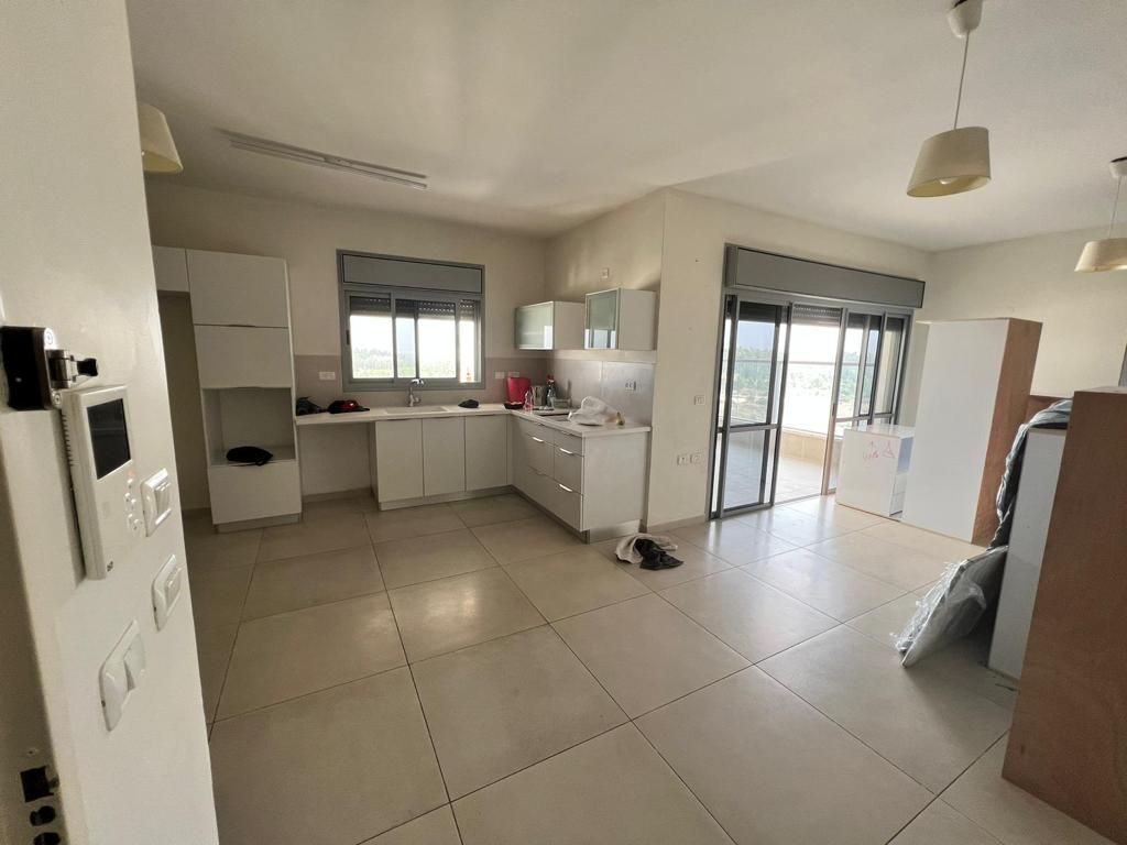 מטבח עם ארונות לבנים ודלת זכוכית הזזה.